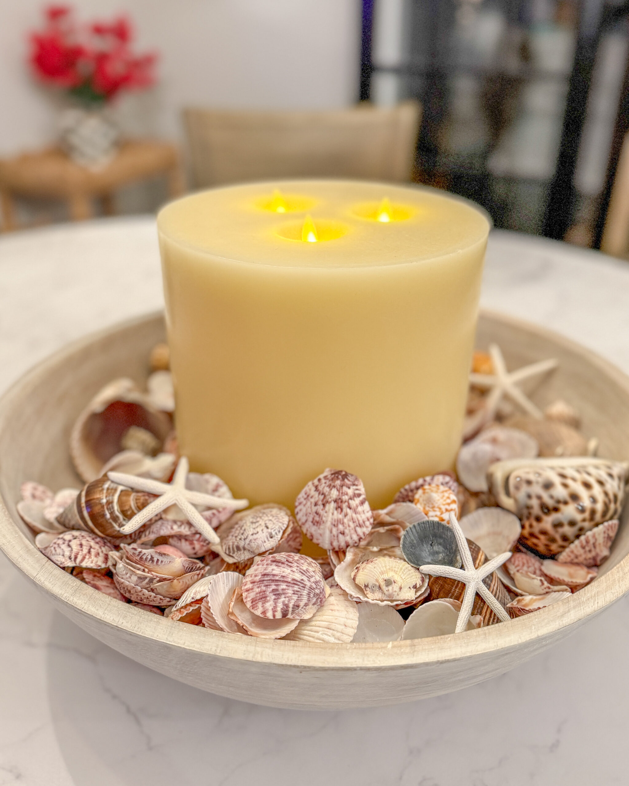 Seashells in a large driftwood bowl with a pillar candle in the middle for a centerpiece