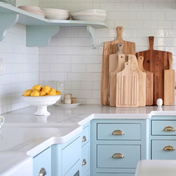 coastal kitchen with soft blue cabinets and cutting boards and a big bowl of lemons